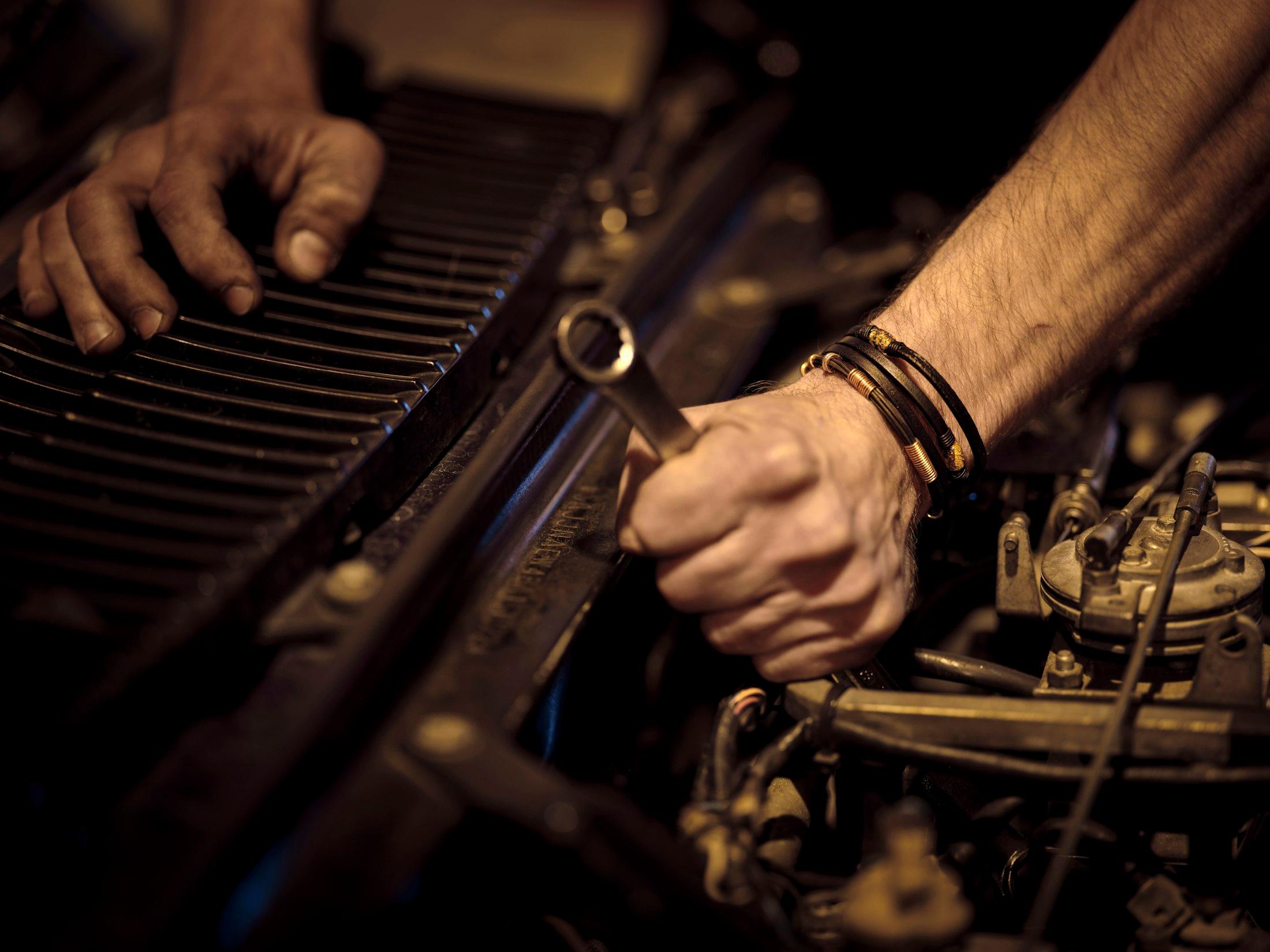 First-person view of a mechanic's hands tightening a bolt with a wrench